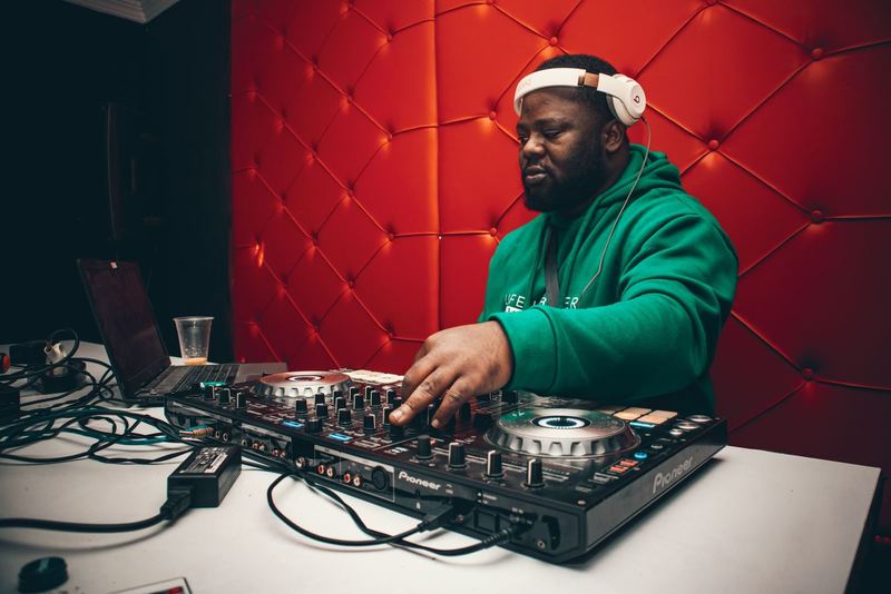 DJ mixing tracks on a turntable with headphones in a vibrant club setting.