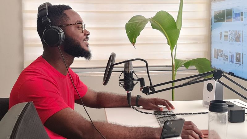 Man recording podcast in home studio with microphone, headphones, and computer screen.