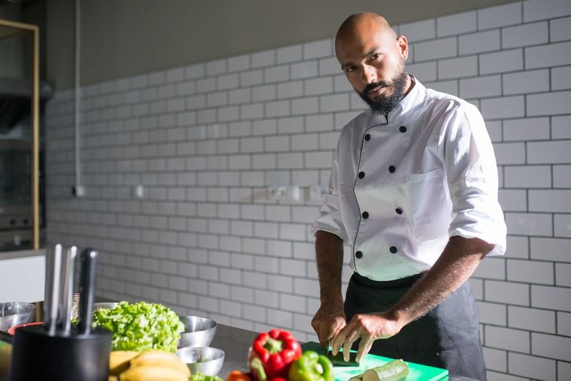 Chef in a professional kitchen slicing vegetables, showcasing culinary skills in Portugal.
