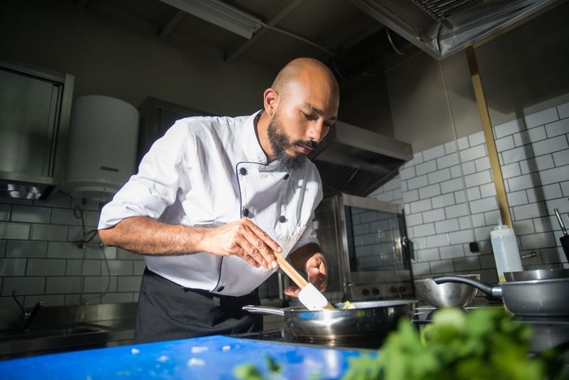 Chef preparing a dish in a modern kitchen, showcasing culinary skills.